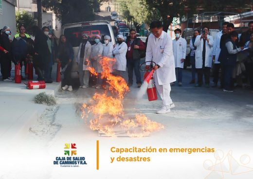 Un médico con bata apaga con un extintor las llamas del simulacro mientras el personal observa.